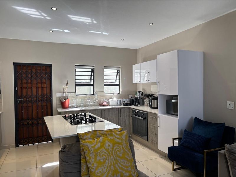 Modern kitchen featuring a central island with a gas hob, built-in oven, sleek cabinetry, quartz countertops, and tiled flooring.