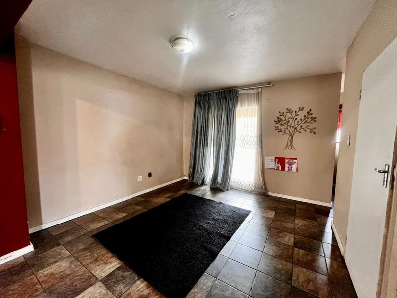 A spacious living area featuring tiled flooring and a sliding glass door providing natural light and access to the exterior.