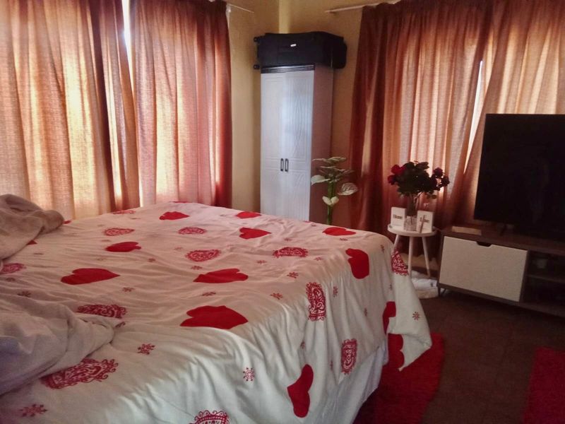 A bedroom featuring a built-in wardrobe and large windows covered by curtains.