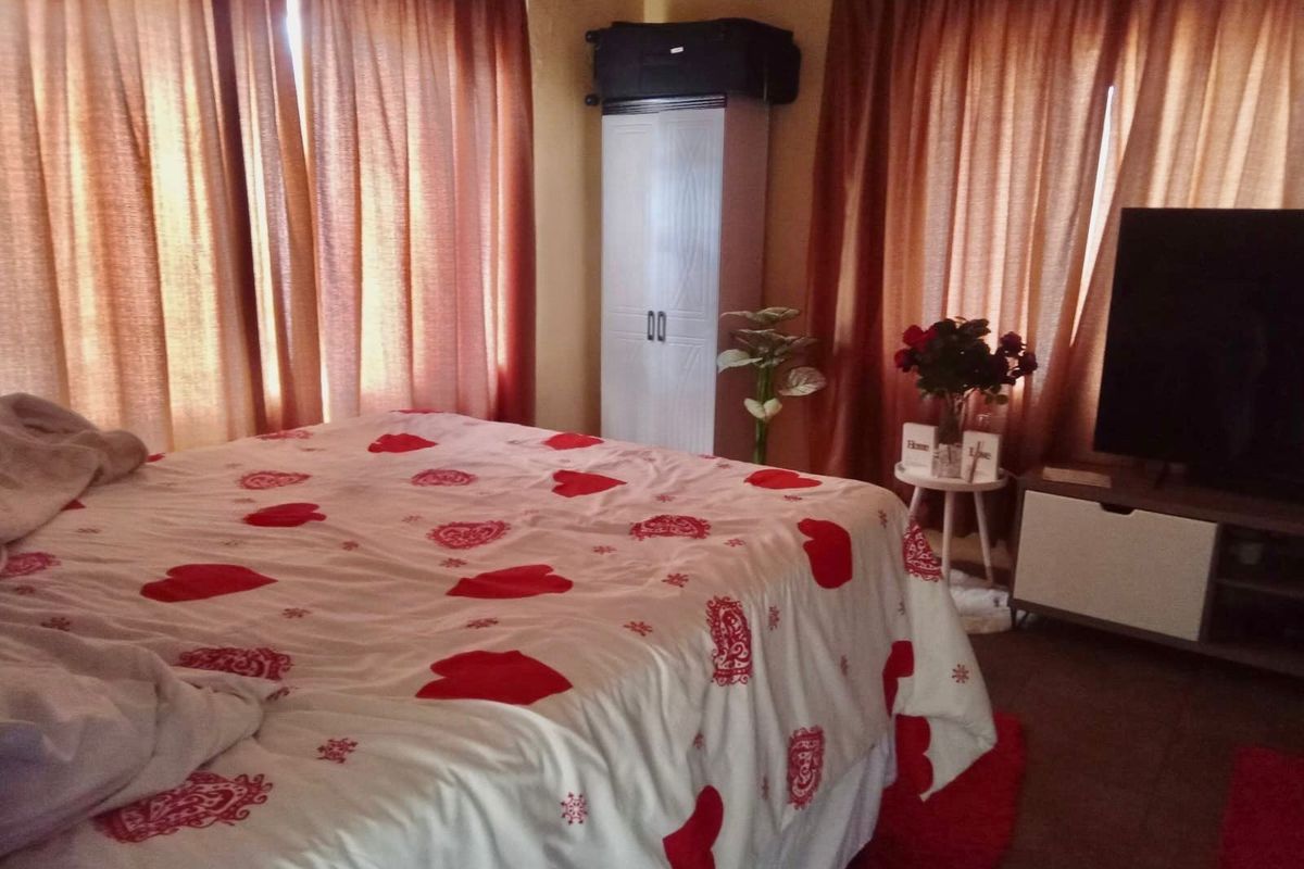 A bedroom featuring a built-in wardrobe and large windows covered by curtains.