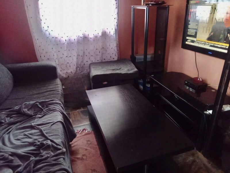 A compact living room area featuring tiled flooring and wall-mounted television setup.