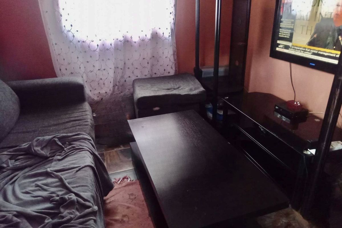 A compact living room area featuring tiled flooring and wall-mounted television setup.