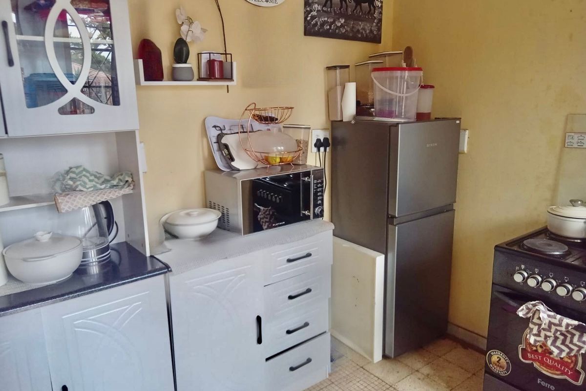 A compact kitchen area featuring built-in cabinetry, a countertop, and an electric stove, requiring cosmetic updates to modernize the space.