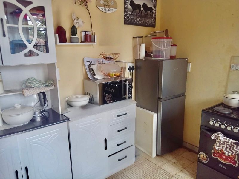 A compact kitchen area featuring built-in cabinetry, a countertop, and an electric stove, requiring cosmetic updates to modernize the space.