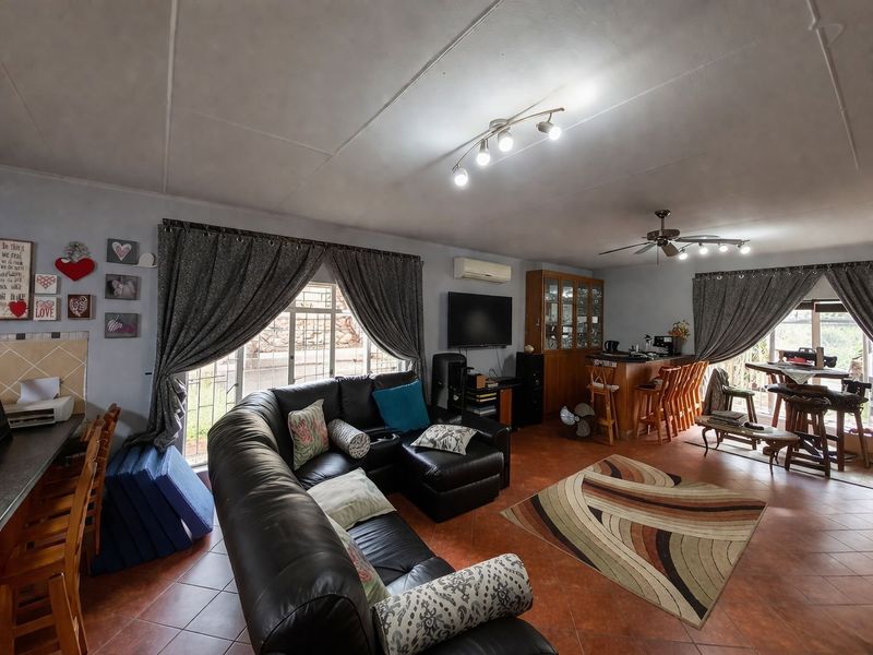 Spacious open-plan living and dining area featuring tiled flooring, a breakfast bar, built-in cabinetry, and a ceiling fan.