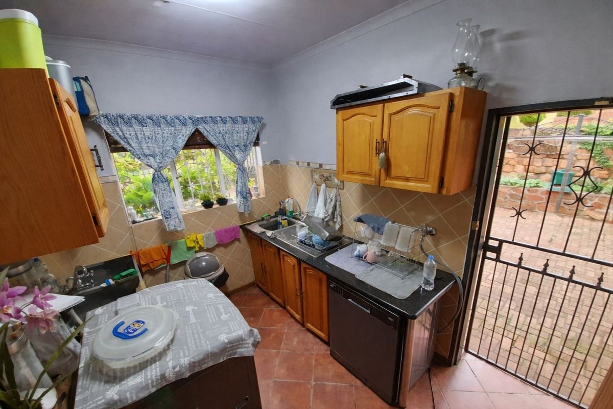 A functional kitchen featuring wooden cabinetry, tiled backsplash, and direct access to the rear outdoor area through a security gate.