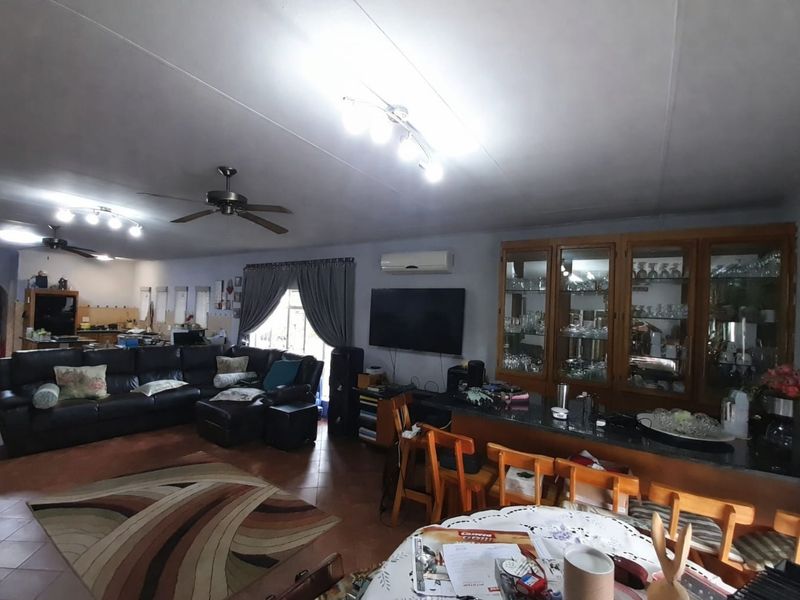 Spacious open-plan living and dining area featuring tiled flooring, a built-in display cabinet, breakfast bar, and integrated climate control.