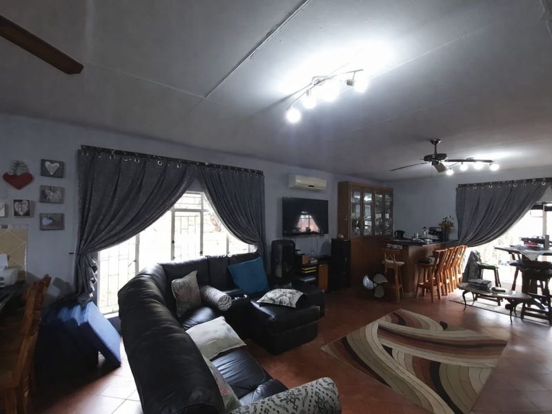 Spacious open-plan living area featuring tiled flooring, a built-in bar, ceiling fans, and a split-system air conditioner.