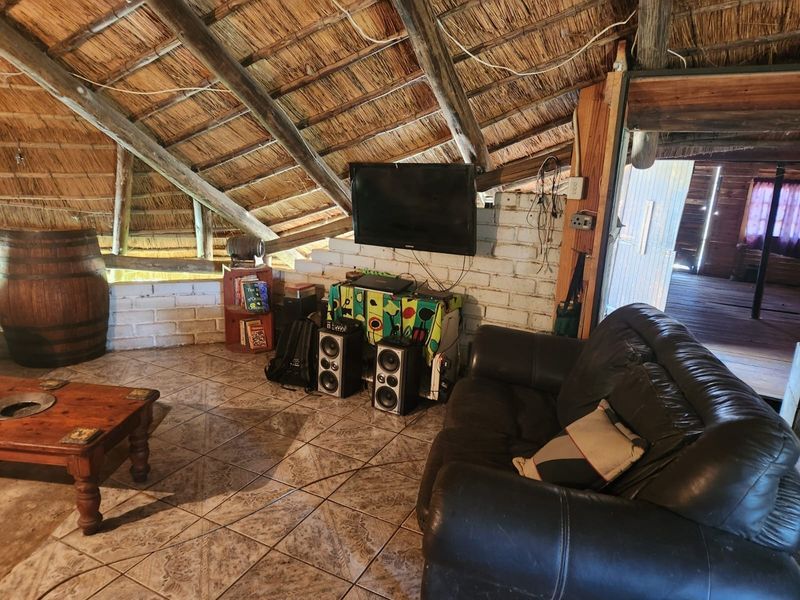 Rustic living area featuring a traditional thatched roof with exposed timber rafters and tiled flooring, offering a unique farm-style aesthetic.