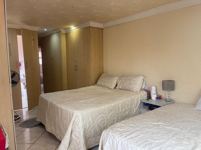 A bedroom featuring built-in wooden cupboards, tiled flooring, and a coved ceiling with recessed lighting.