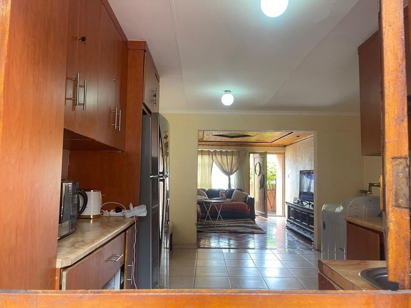 Open plan kitchen and living area featuring laminate cabinetry, tiled flooring, and direct access to an outdoor patio space.