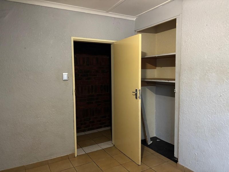An empty bedroom featuring tiled flooring and a built-in cupboard, requiring cosmetic updates to improve its overall condition and appeal.