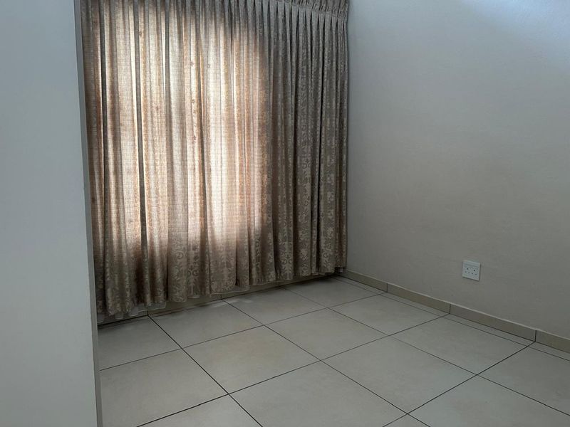An empty bedroom featuring neutral tiled flooring and full-length curtain tracks, providing a blank canvas for personalization.