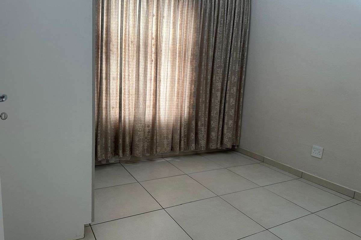 A clean, empty bedroom featuring neutral tiled flooring and full-length curtain tracks, providing a blank canvas for personalization.