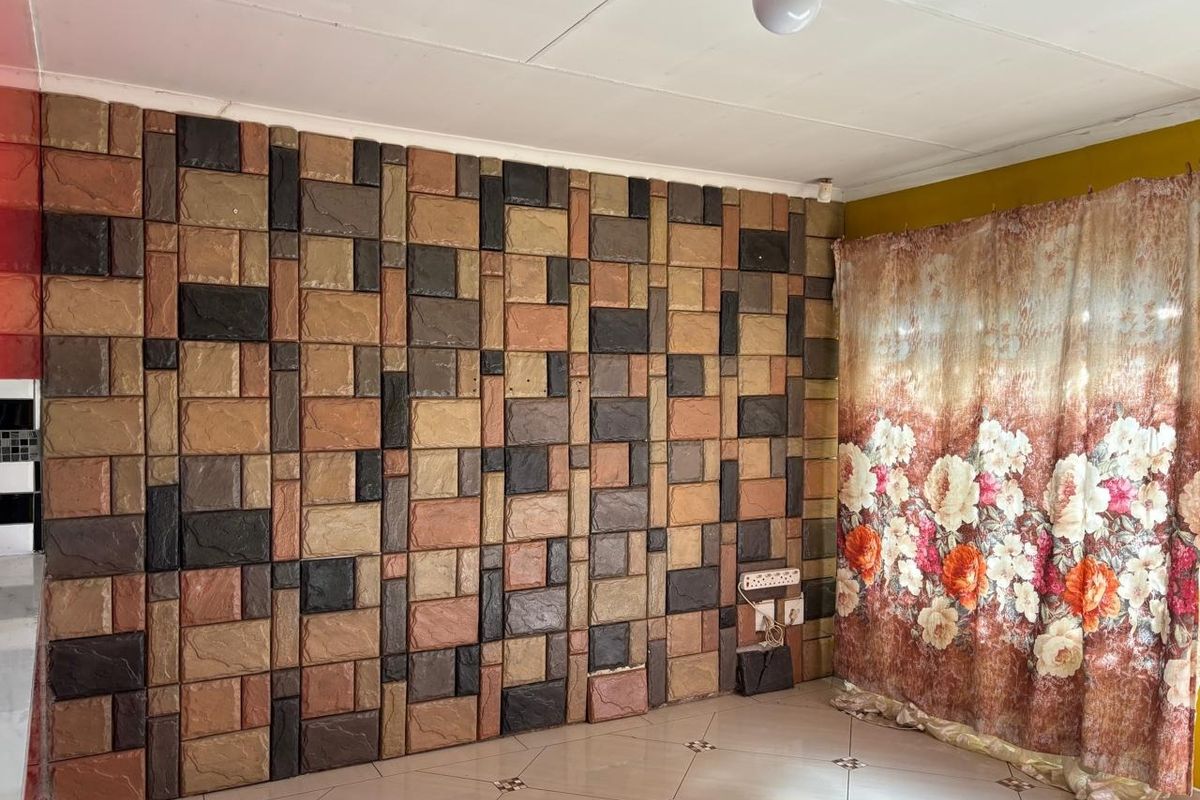 Living area featuring a decorative stone-effect feature wall and tiled flooring, requiring minor repairs to wall finishes.
