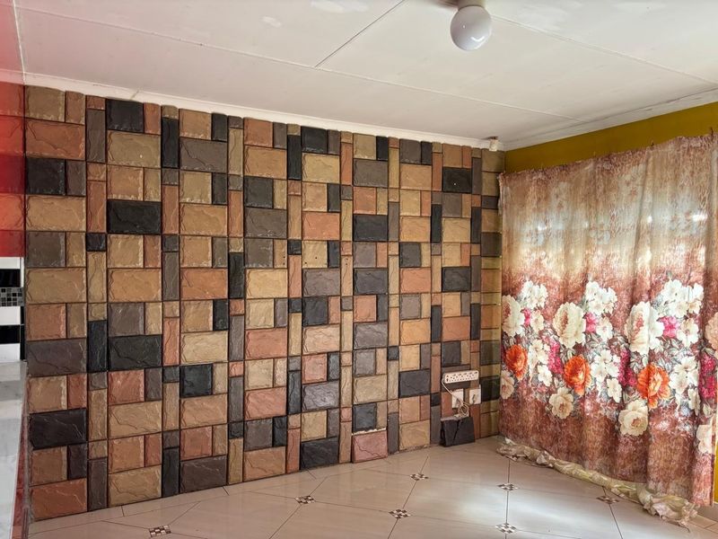 Living area featuring a decorative stone-effect feature wall and tiled flooring, requiring minor repairs to wall finishes.