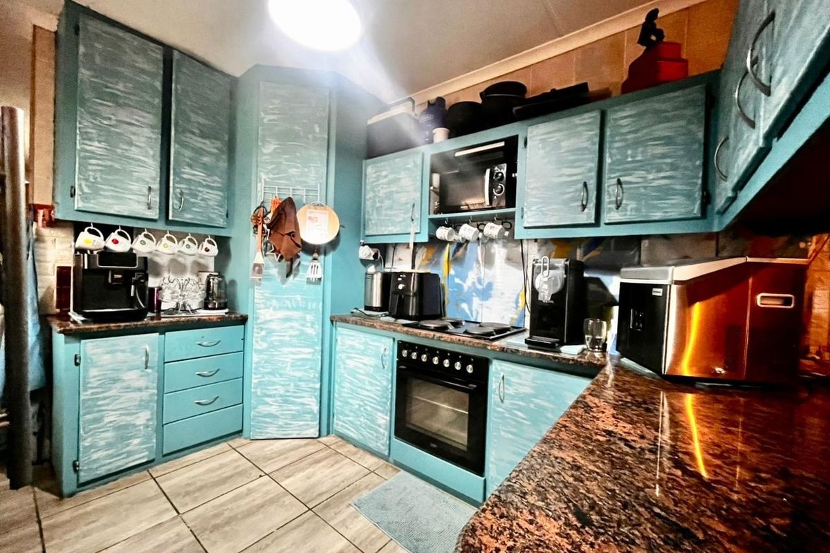 A functional kitchen featuring blue painted cabinetry, granite countertops, and built-in cooking appliances with tiled flooring and backsplash.
