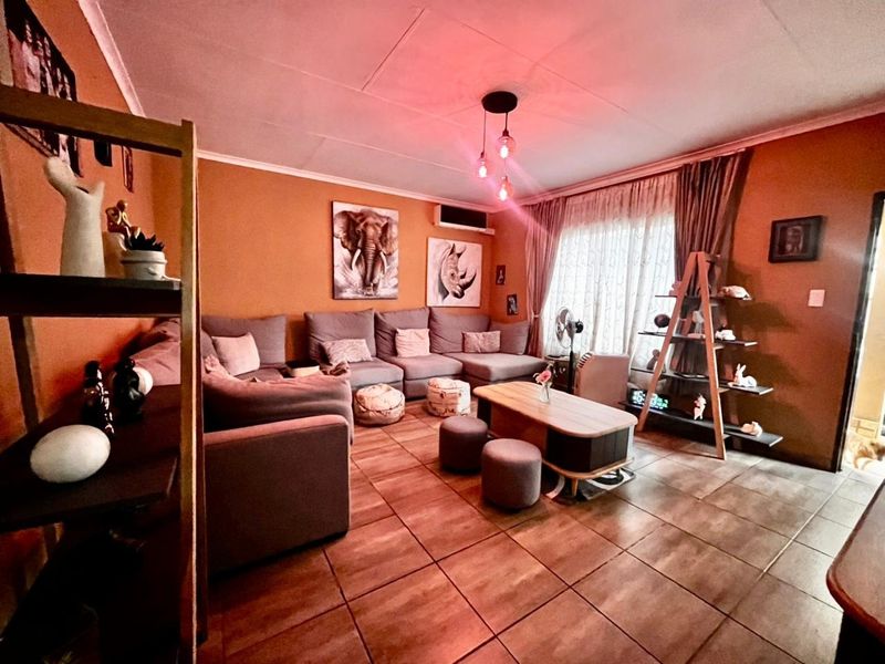 A cozy living room featuring tiled flooring, a wall-mounted air conditioning unit, and warm ambient lighting.