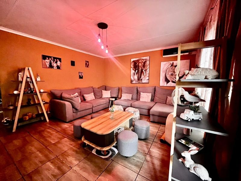 A cozy living room featuring tiled flooring, a wall-mounted air conditioning unit, and modern pendant lighting.