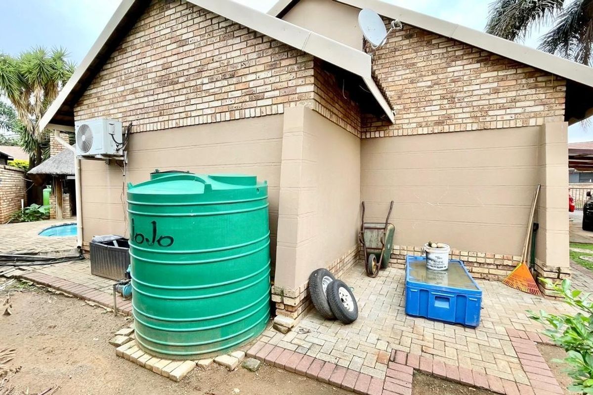 Rear exterior view of the house featuring a brick facade, paved patio area, and a large water storage tank.