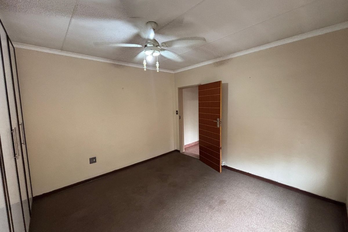 An empty bedroom featuring built-in cupboards, a ceiling fan, and carpeted flooring, ready for a fresh update.