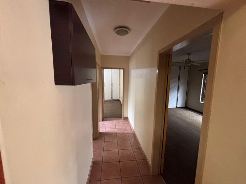 A functional hallway featuring tiled flooring and a built-in wall cabinet, providing access to adjacent rooms.