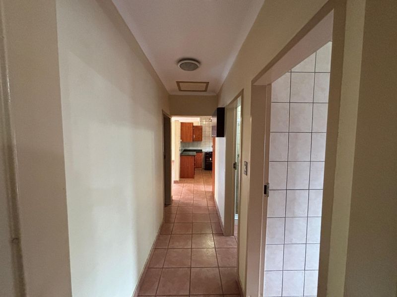 A functional hallway with tiled flooring leading towards the kitchen area, featuring neutral wall finishes and standard door frames.