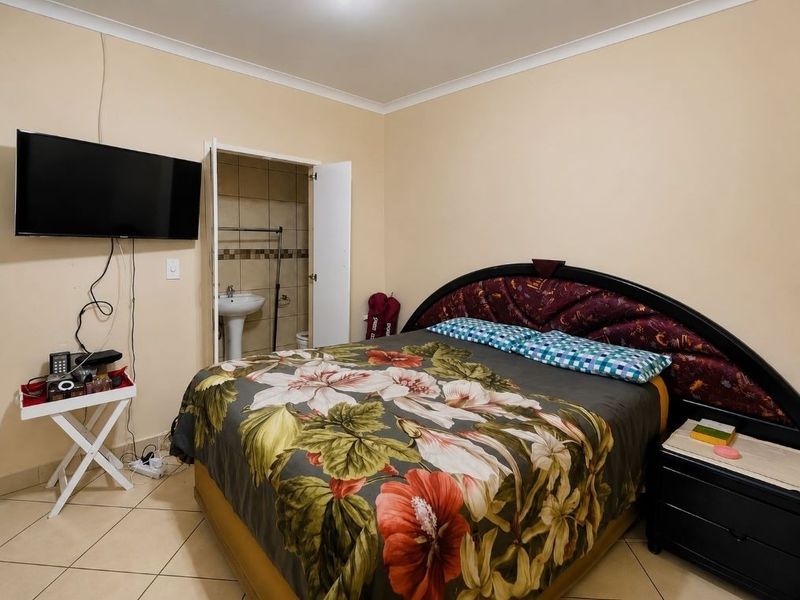 A bedroom featuring tiled flooring and an attached en-suite bathroom with a pedestal basin.