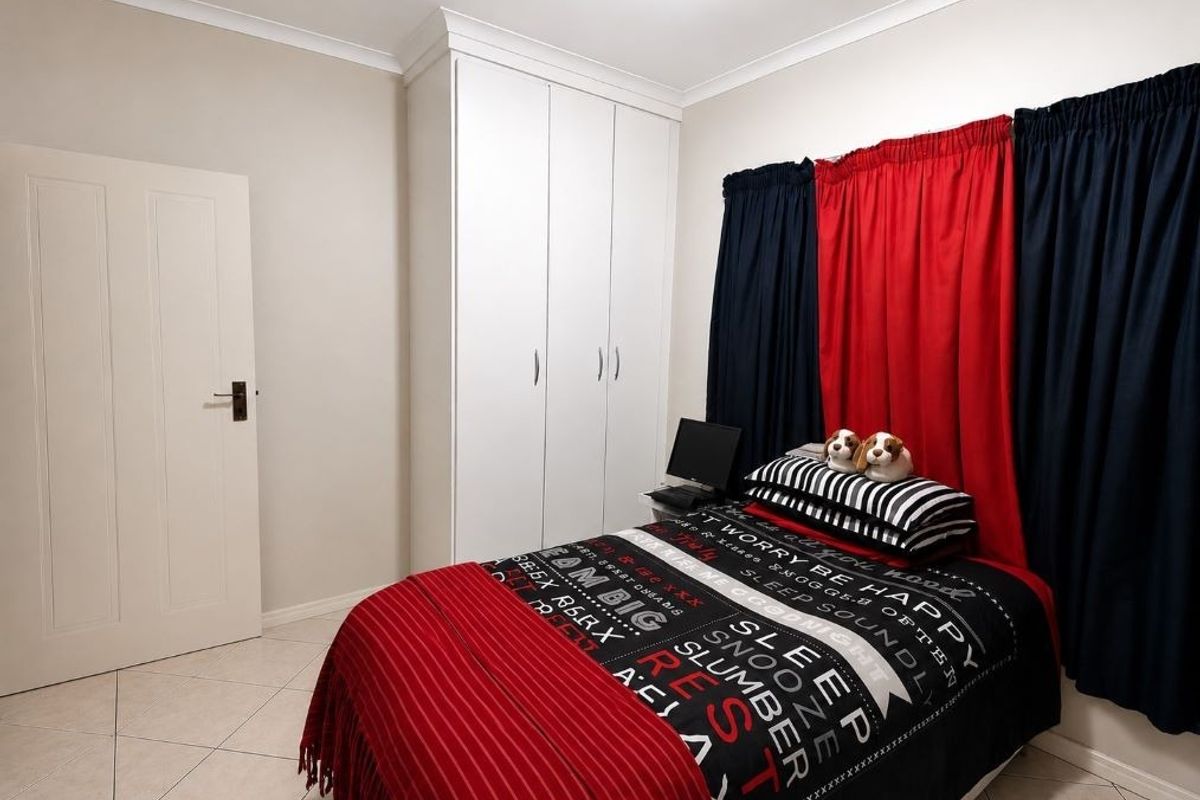 A well-maintained bedroom featuring neutral tiled flooring, white built-in cupboards, and classic cornice detailing, offering a clean and functional living space.