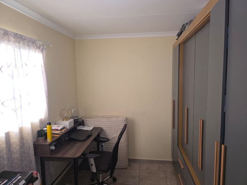 A bedroom featuring tiled flooring and a modern built-in wardrobe with wood-trim detailing.