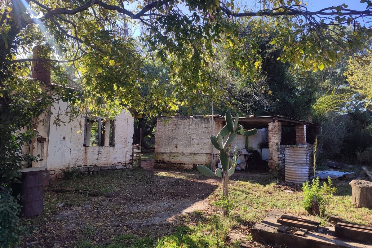 Rear view of a farm property showing weathered brick structures and outbuildings in need of significant renovation and maintenance.