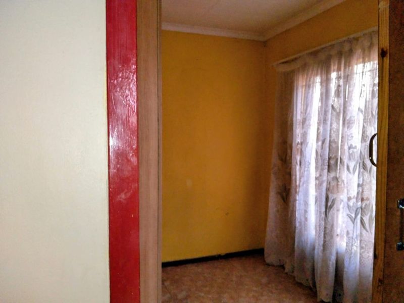 An empty bedroom featuring yellow painted walls, coving, and skirting boards, viewed through a doorway.