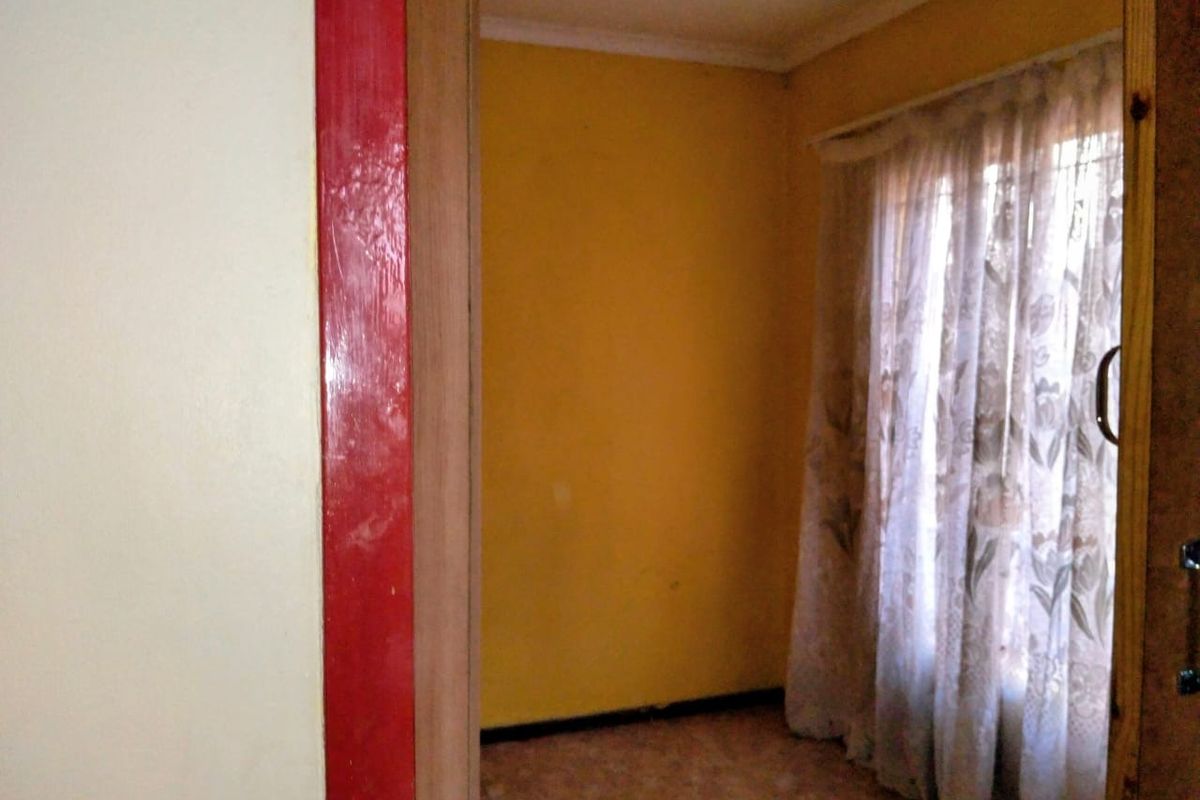 An empty bedroom featuring yellow painted walls, coving, and skirting boards, viewed through a doorway.