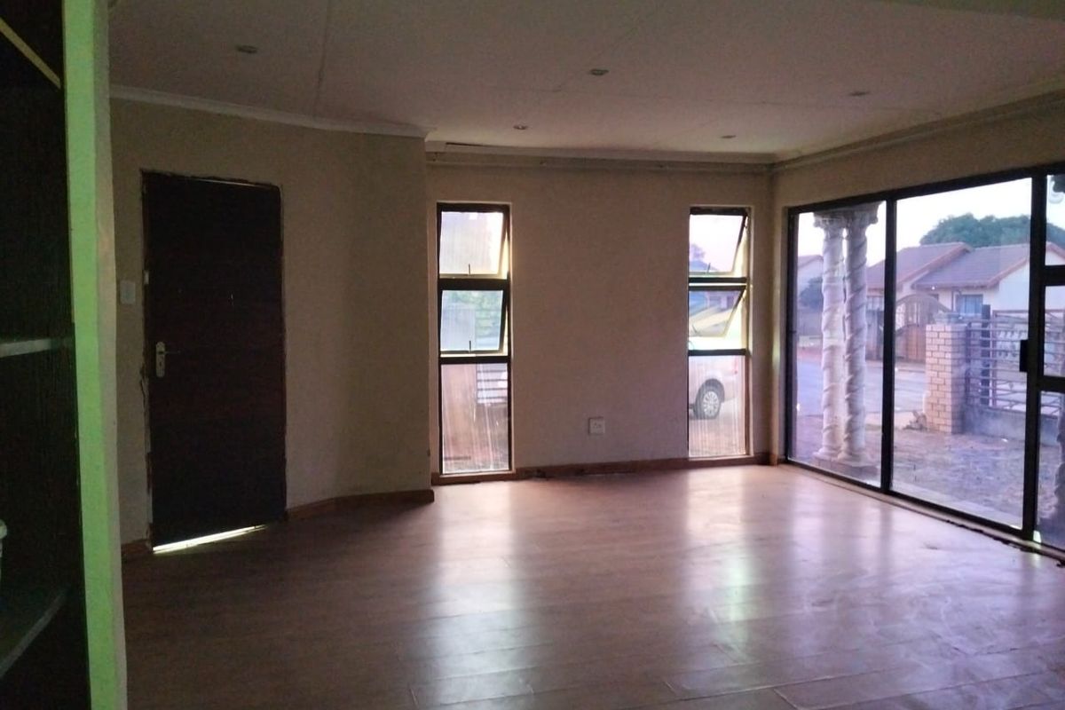 An empty living room featuring laminate flooring, recessed lighting, and large sliding glass doors providing natural light and access to the exterior.