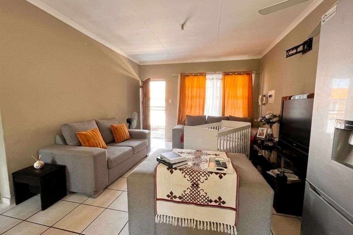 A functional living room featuring tiled flooring, a ceiling fan, and direct access to an exterior area through a doorway.