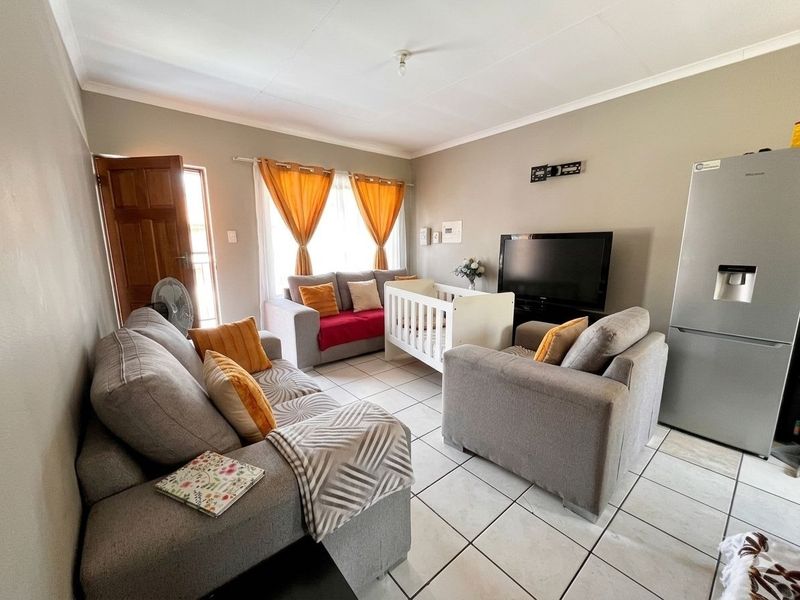 A living room area featuring tiled flooring, a timber entrance door, and curtain rails, providing a functional and open living space.