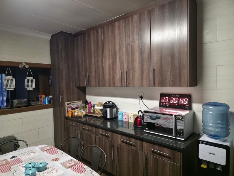 A functional kitchen featuring dark wood-grain cabinetry, granite countertops, and a neutral tiled backsplash, providing ample storage and workspace.