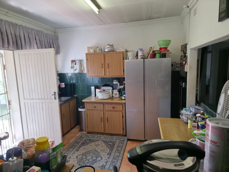 A functional kitchen featuring dated wooden cabinetry, tiled backsplash, and direct access to the exterior, offering potential for a modern renovation.