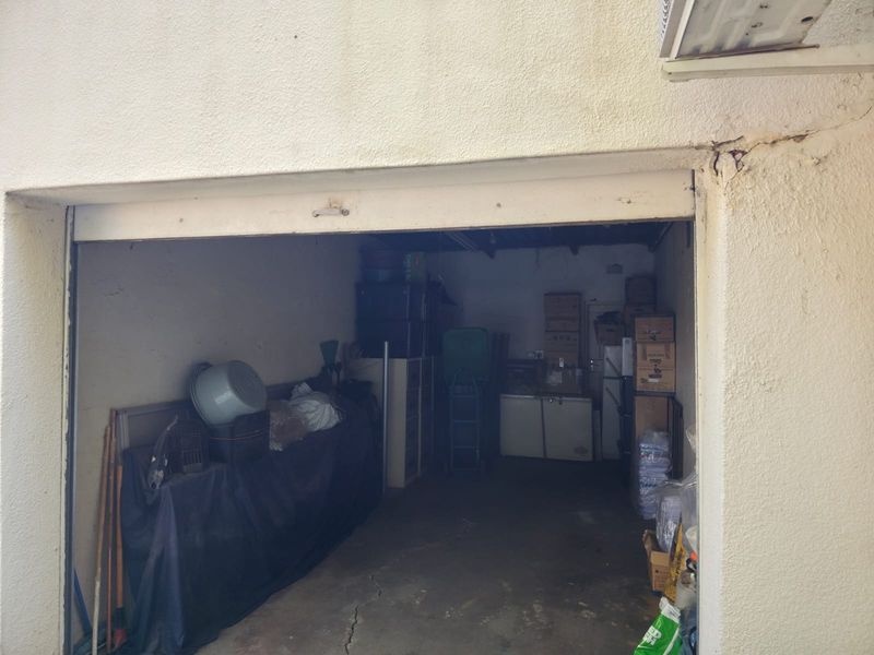 A functional garage space featuring a concrete floor and exterior stucco finish, currently used for storage.