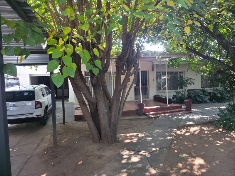 Front view of the property featuring a covered carport, tiled entrance porch, and a paved walkway leading to the main entrance.