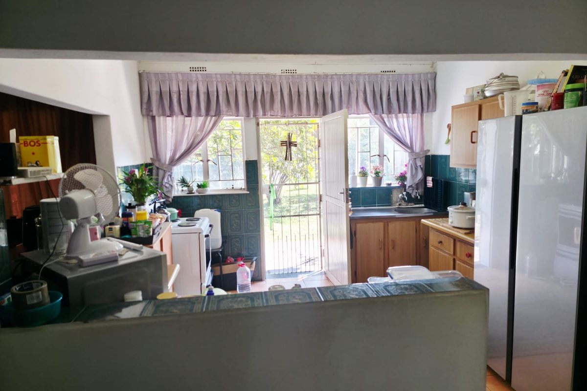 A functional kitchen featuring built-in cabinetry, tiled splashbacks, and direct access to the rear garden through a security gate.