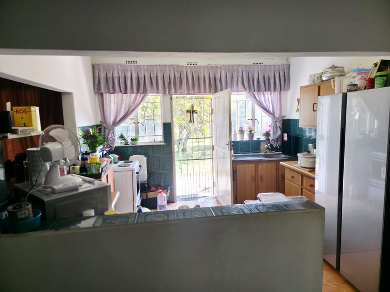 A functional kitchen featuring built-in cabinetry, tiled splashbacks, and direct access to the rear garden through a security gate.