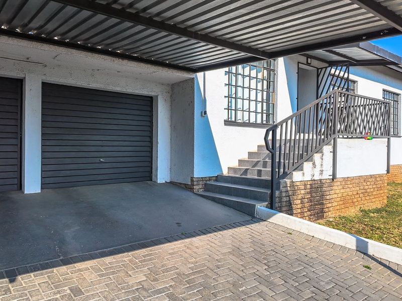 Front exterior view featuring a covered carport, garage access, and a concrete staircase leading to the main entrance.