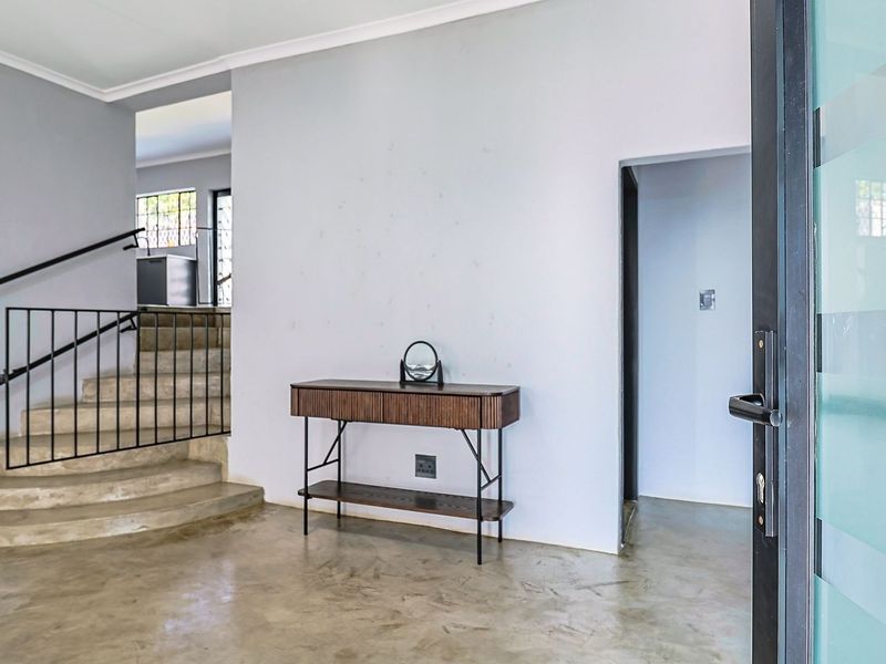 Entrance foyer featuring polished concrete flooring, a concrete staircase with a modern metal handrail, and a contemporary frosted glass front door.