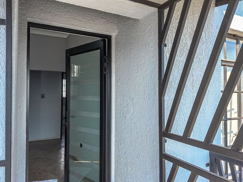 Entrance area featuring a modern glass door and a secure metal gate, providing access to the interior living space.