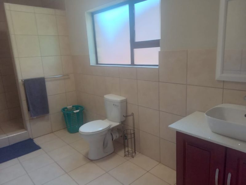 A functional bathroom featuring tiled walls and flooring, a vanity with a vessel sink, a toilet, and a separate shower enclosure.