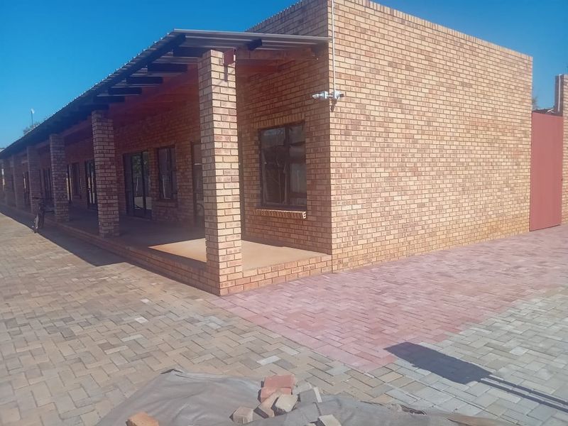 Exterior view of a face brick apartment building featuring a covered patio area and paved driveway.