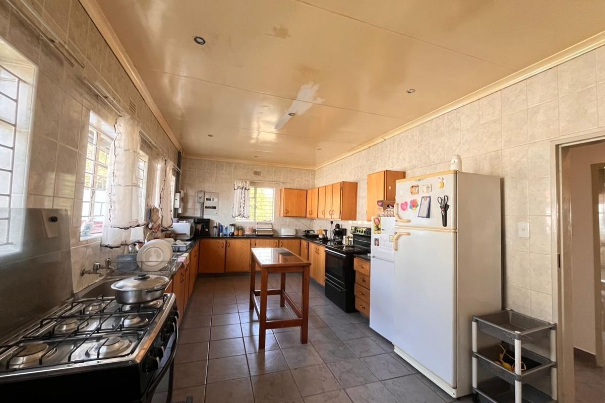 Spacious kitchen featuring wooden cabinetry, tiled finishes, and a gas stove, currently showing signs of ceiling wear and requiring cosmetic updates.