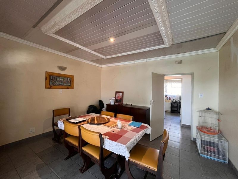 Dining room featuring tiled flooring and a decorative ceiling panel, with direct access to the adjacent kitchen area.