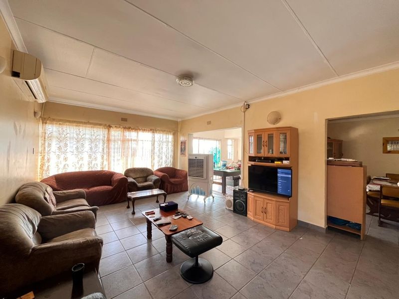 Spacious living room featuring tiled flooring and an integrated air conditioning unit, offering a functional layout with potential for cosmetic updates.